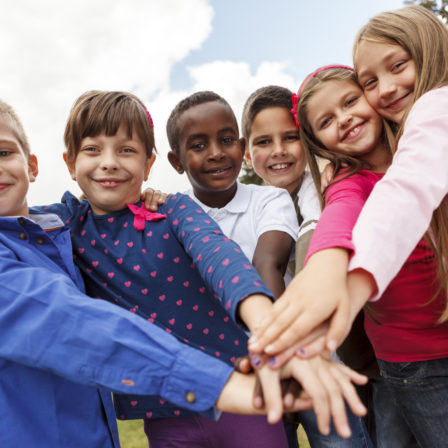 Multiracial school children putting their hands together