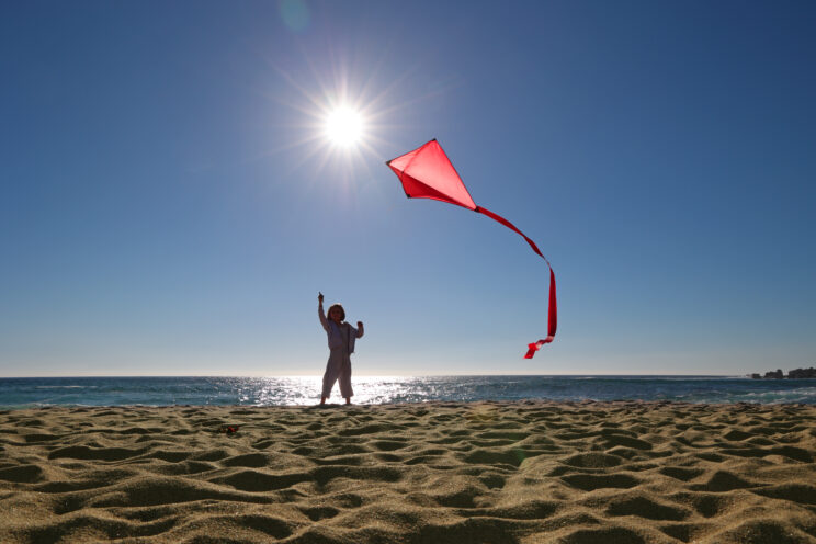 Young girl flying kite on beach