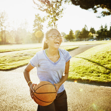 Young woman playing basketball on outdoor court